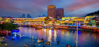 The night lights with vibrant colors in Singapore's Clarke Quay area, with passersby enjoying the riverside walk