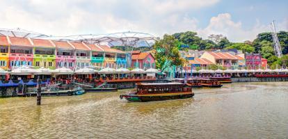 Colorful buildings stand out next to a passenger boat in Singapore's Clark Quay