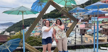 Two friends pose together in front of Gamcheong Village in Busan, South Korea