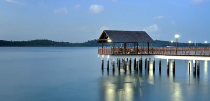 Evening reflections of jetty over lake at Changi, with gentle clouds in the sky