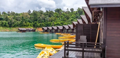 Overwater bungalows with kayaks next to lush outcrop of land in Khao Sok National Park