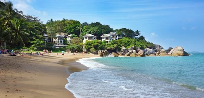White bungalows in the jungle line Coral Cove beach in Koh Samui, Thailand