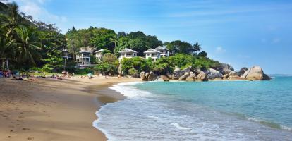 White bungalows in the jungle line Coral Cove beach in Koh Samui, Thailand