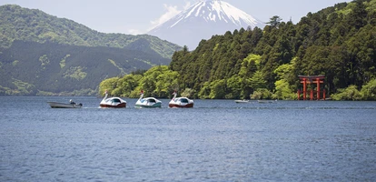 Small boat tows duck floaters in with Mount Fuji in the background in Lake Ashi, in the Hakone area of Japan