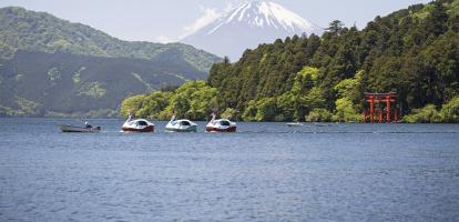 Small boat tows duck floaters in with Mount Fuji in the background in Lake Ashi, in the Hakone area of Japan