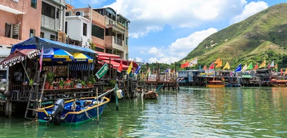 Fishing boats docked up by covered jetties alongside colorful houses in Tai O Village in Hong Kong's Lantau Island