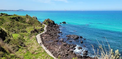 Hikers walk along the Handam Coast trail surrounded by azure waters in Jeju island