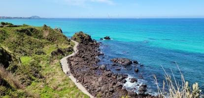 Hikers walk along the Handam Coast trail surrounded by azure waters in Jeju island