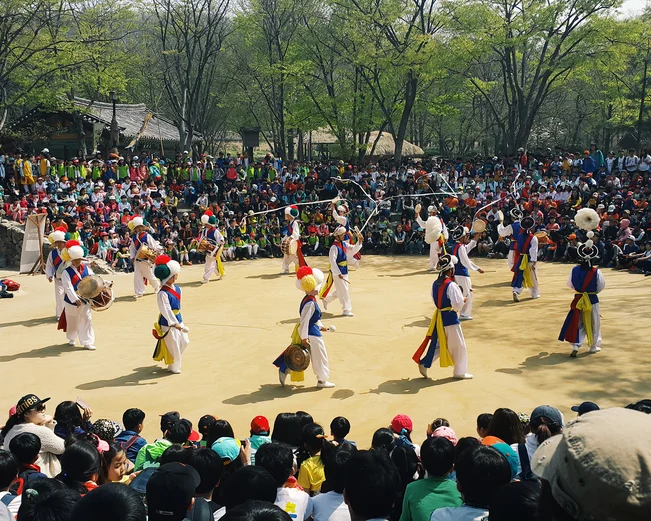 Dancers in traditional costume in circle surrounded by crowds of spectators 