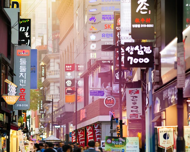 People walking along Myeongdong shopping street surrounded by neon signs 