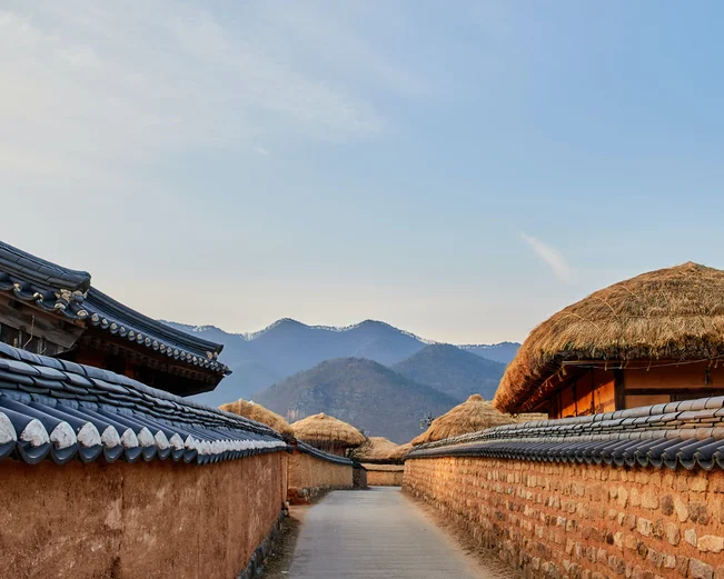 Traditional thatched houses in Andong village with mountains in background