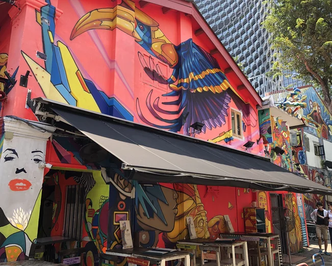 Street art on side of restaurant building beneath modern skyscrapers 