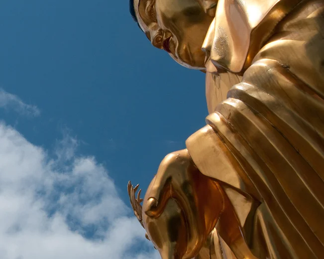 Golden Buddha statue with sky in background 