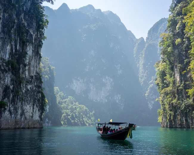 Boat on lagoon in Khao Sok surrounded by steep karst cliffs 