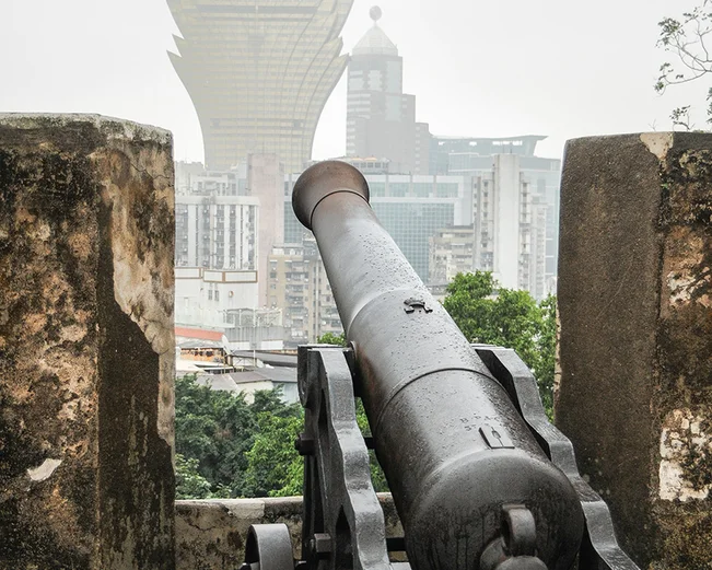 Cannon pointing through wall on misty day 