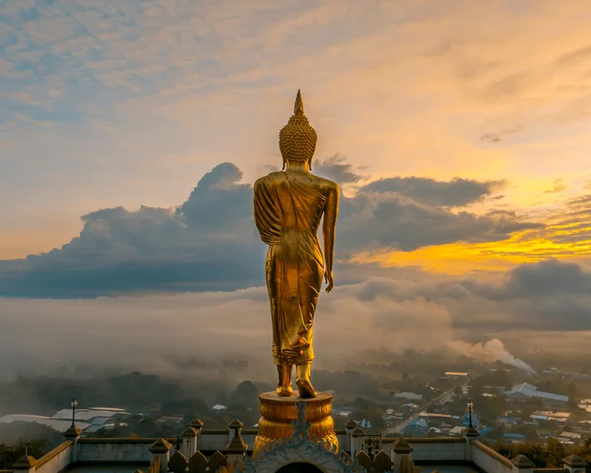 Golden Blessing Buddha overlooking Nan skyline at sunset