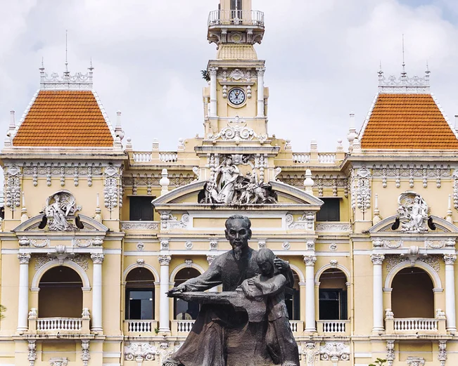Statue in front of colonial building with Vietnamese flag in Ho Chi Minh City, Vietnam