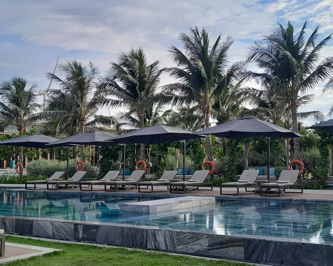Sun loungers and palm trees next to hotel pool