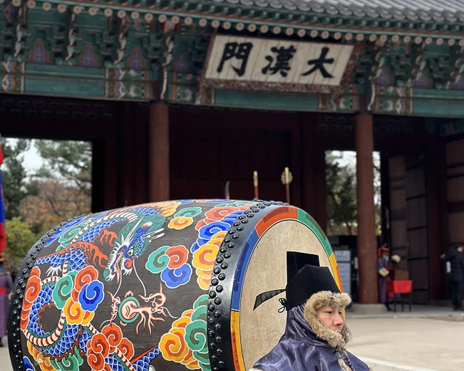 Man in traditional dress with colourful drum at temple in Seoul 