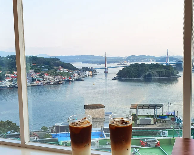 Tall iced coffee drinks and cake on a tray overlooking Yeosu seaside 