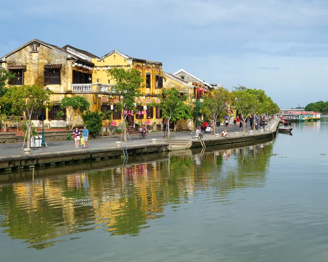 Tourists walk in Hoi An's riverside promenade during the day in Vietnam