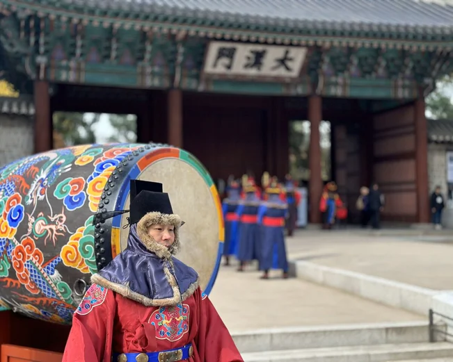 Korean man in traditional dress in front of a ceremonial drum