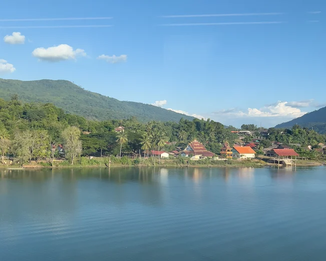 A view from a train window of Laos countryside and water on a Laos by Rail itinerary