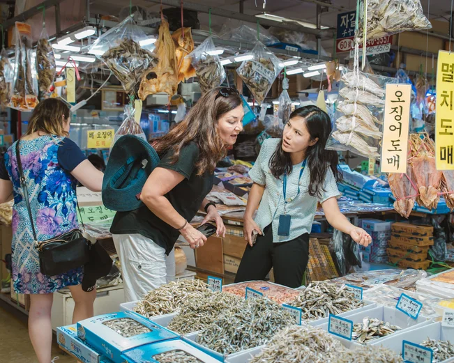 A local Korean guide and a tourist at a fish market in Busan
