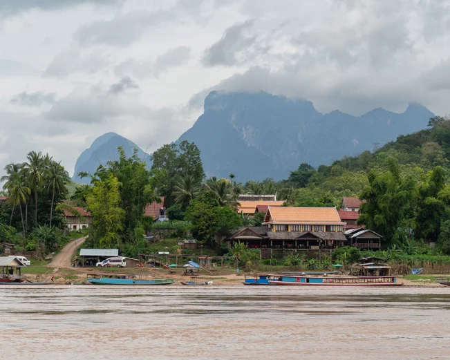 Longtail boats parked at the shore of a small village along the Mekong River
