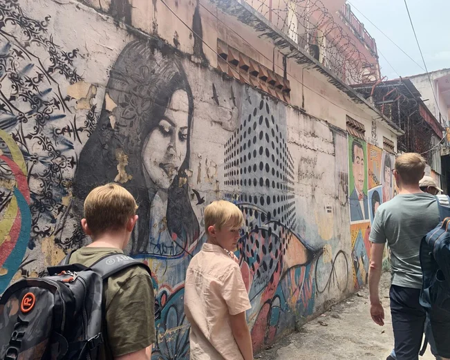 Family walking down Phnom Penh street looking at street art