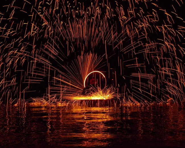 A performer in a fire show, surrounded by glowing sparks