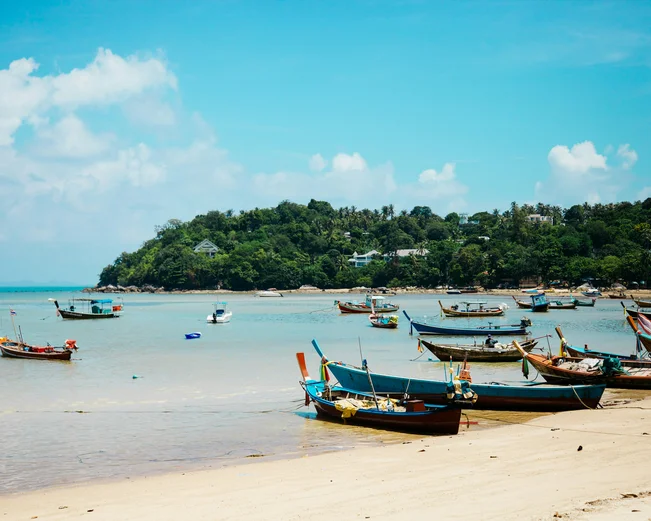 Longtail boats pulled up on the shore on a beach in Ko Samui