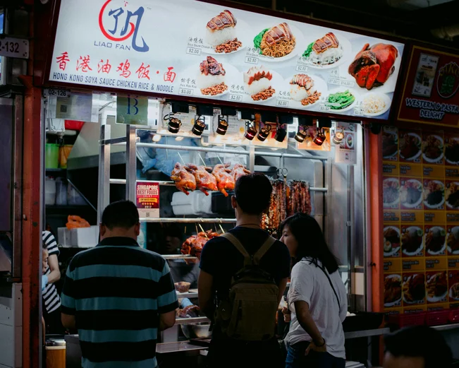 Three people queue up outside a Chicken Rice stand