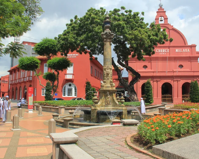 Teracotta-coloured colonial style buildings surround a town square
