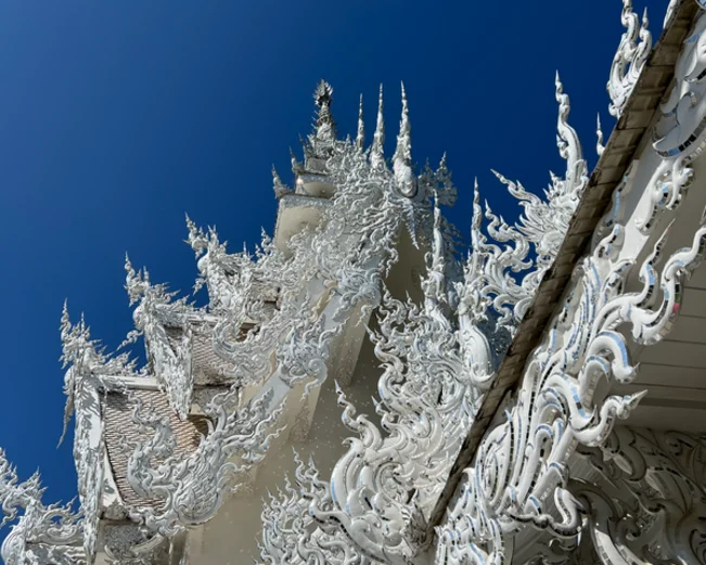 close up of white intricate carvings on the roof of a temple