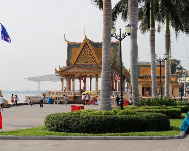 Palm trees and a small pagoda at a riverfront promenade