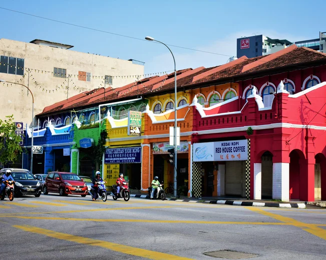 A row of shophouses, each painted a different rainbow colour