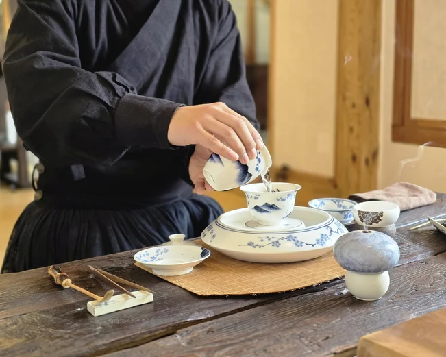 A man pouring tea with a delicate porcelin tea set 
