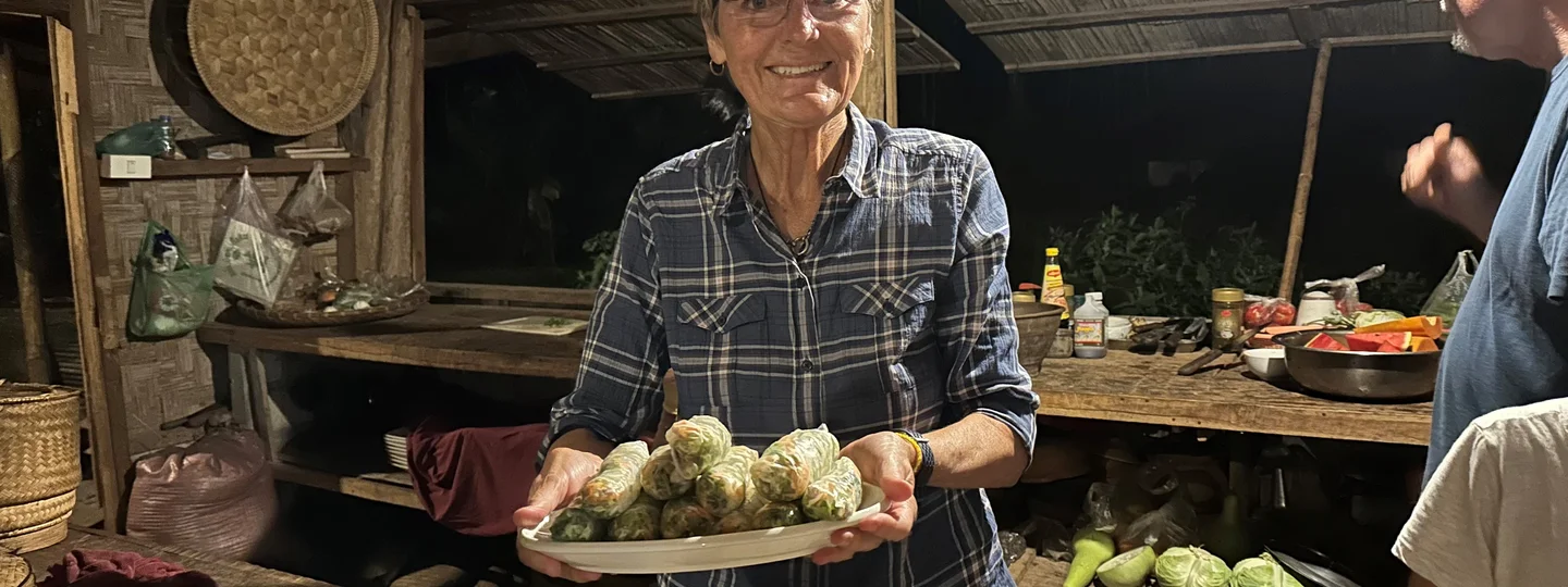 Tourist making summer rolls with local Laos family