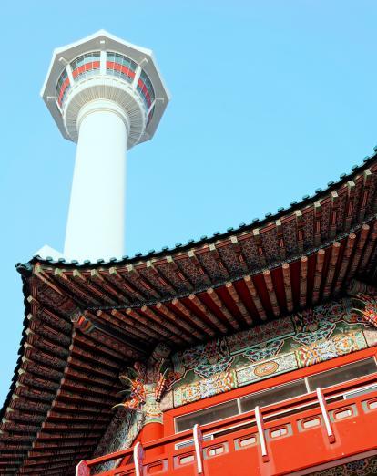 Ornate red temple roof with white Busan Tower in background