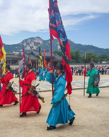 Procession of guards in brightly coloured traditional costume carrying flags