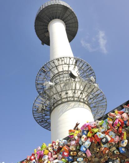 Looking directly up at Seoul Tower past fence with colourful padlocks