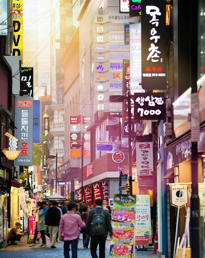 People walking along Myeongdong shopping street surrounded by neon signs 