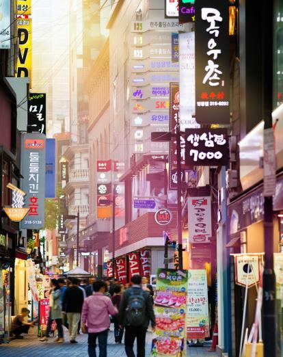 People walking along Myeongdong shopping street surrounded by neon signs