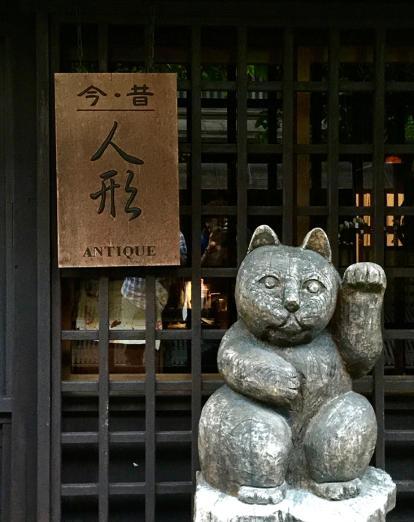 Stone statue of waving cat in front of restaurant door 
