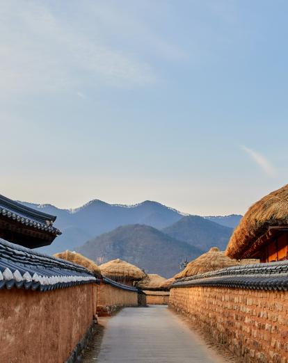 Traditional thatched houses in Andong village with mountains in background