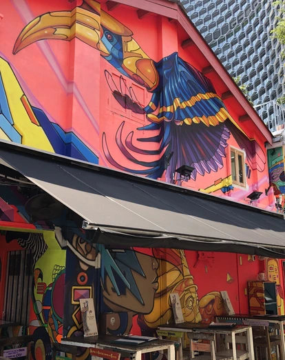 Street art on side of restaurant building beneath modern skyscrapers