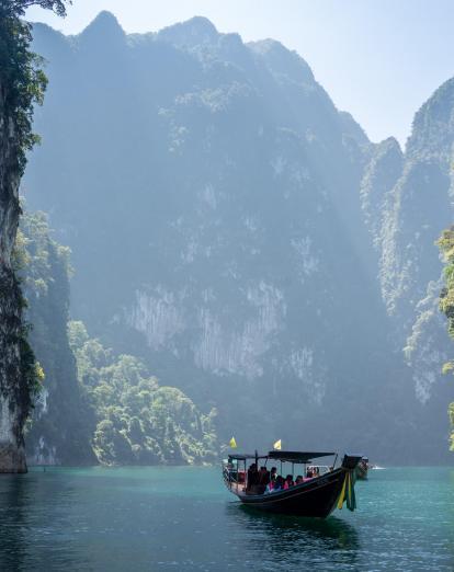 Boat on lagoon in Khao Sok surrounded by steep karst cliffs