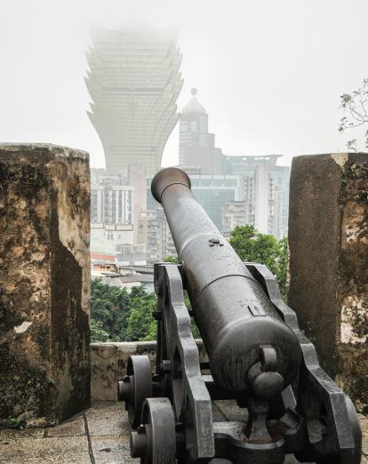 Cannon pointing through wall on misty day