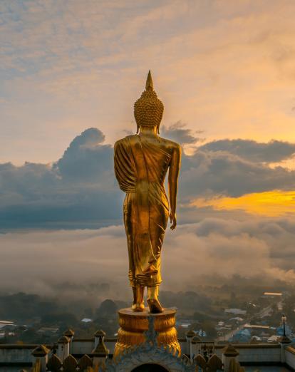 Golden Blessing Buddha overlooking Nan skyline at sunset